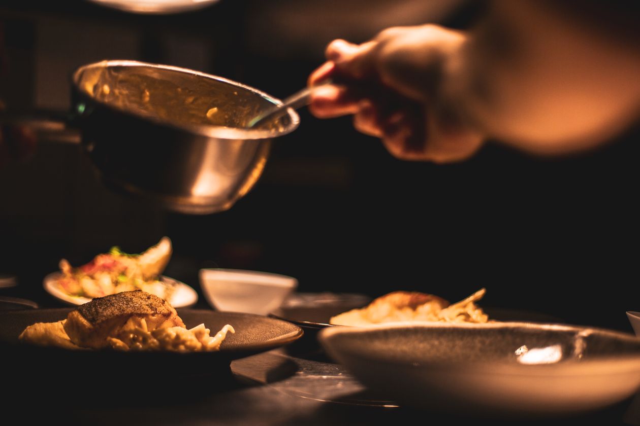 Chef plating a gourmet dish in a professional restaurant kitchen for photography
