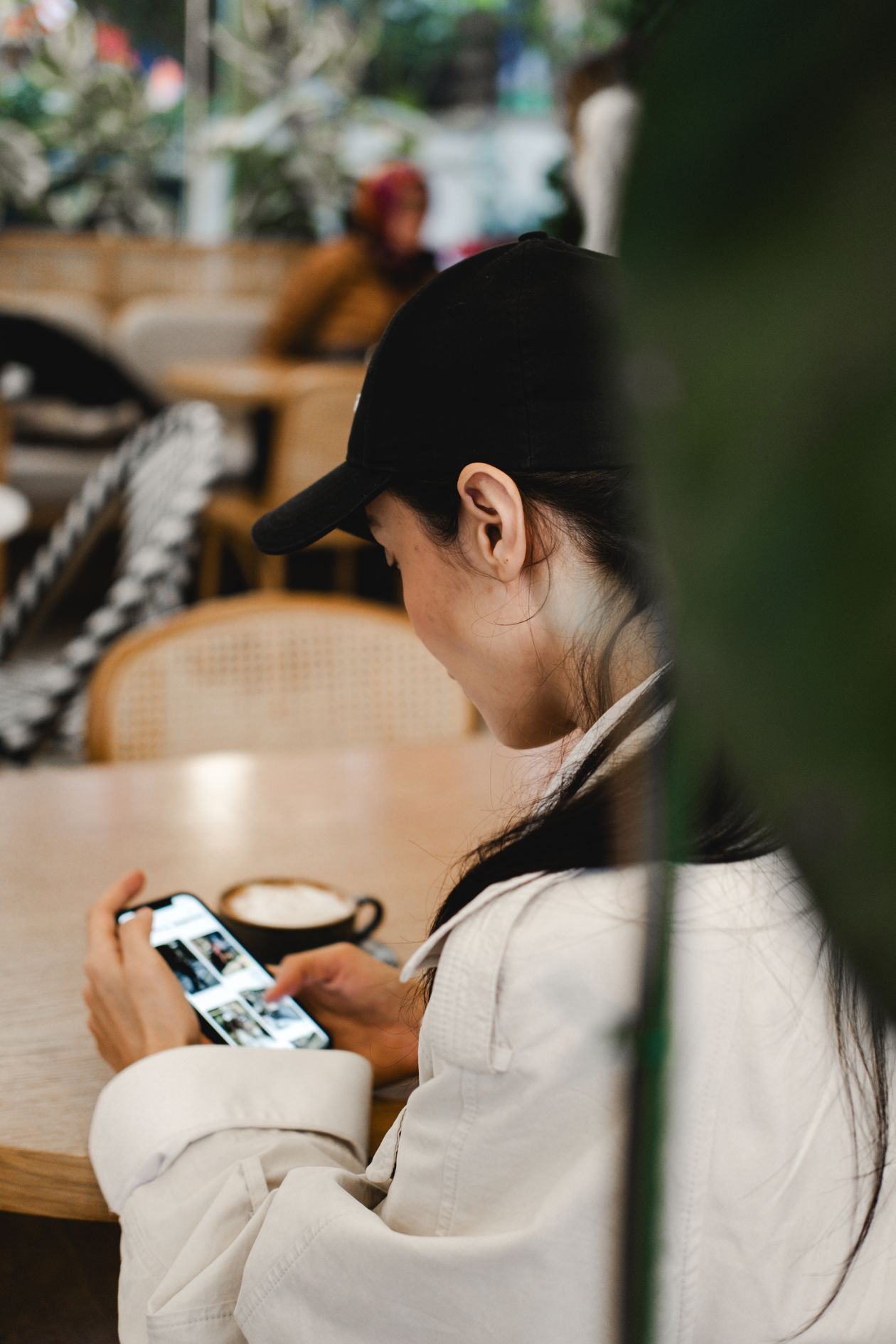 Diner checking phone at a restaurant table, browsing a food delivery app menu