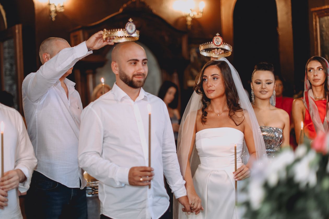 Bride and groom holding candles during an elegant wedding ceremony surrounded by guests, multi-camera wedding videography coverage
