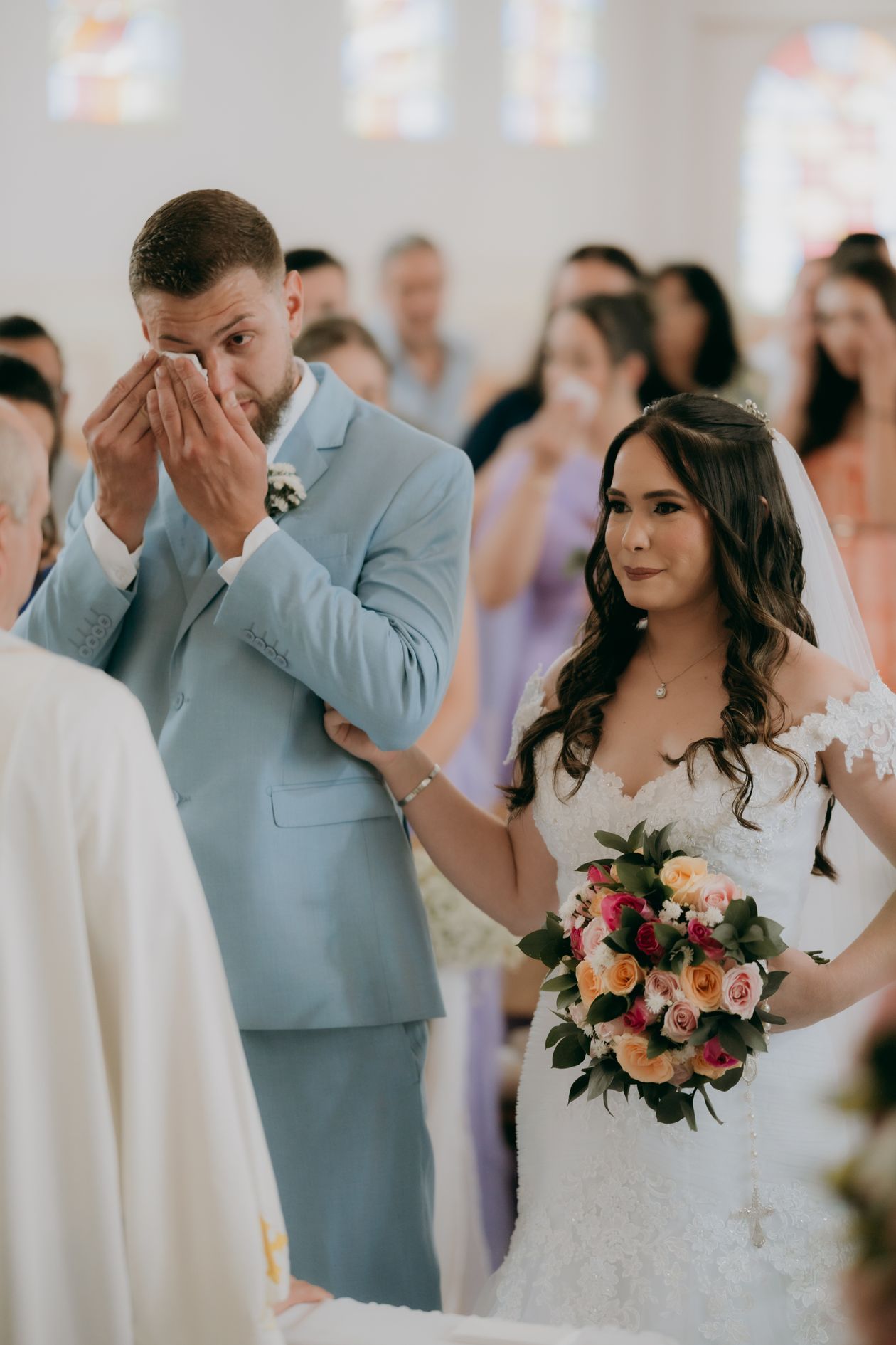 Emotional reaction shot of bride and groom during wedding ceremony with guests in the background