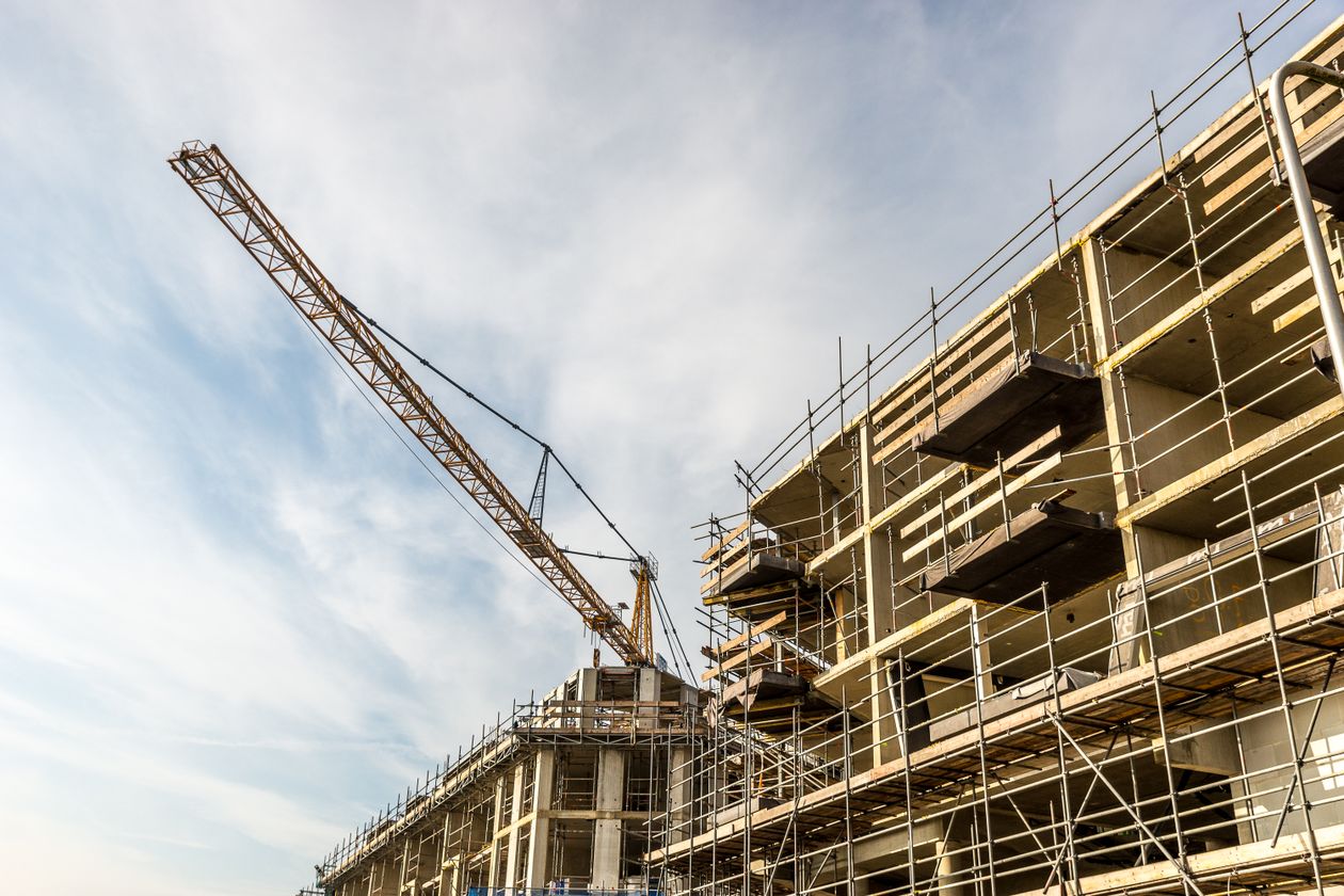 Construction crane and scaffolding on an active building site during daytime, off-plan construction progress documentation