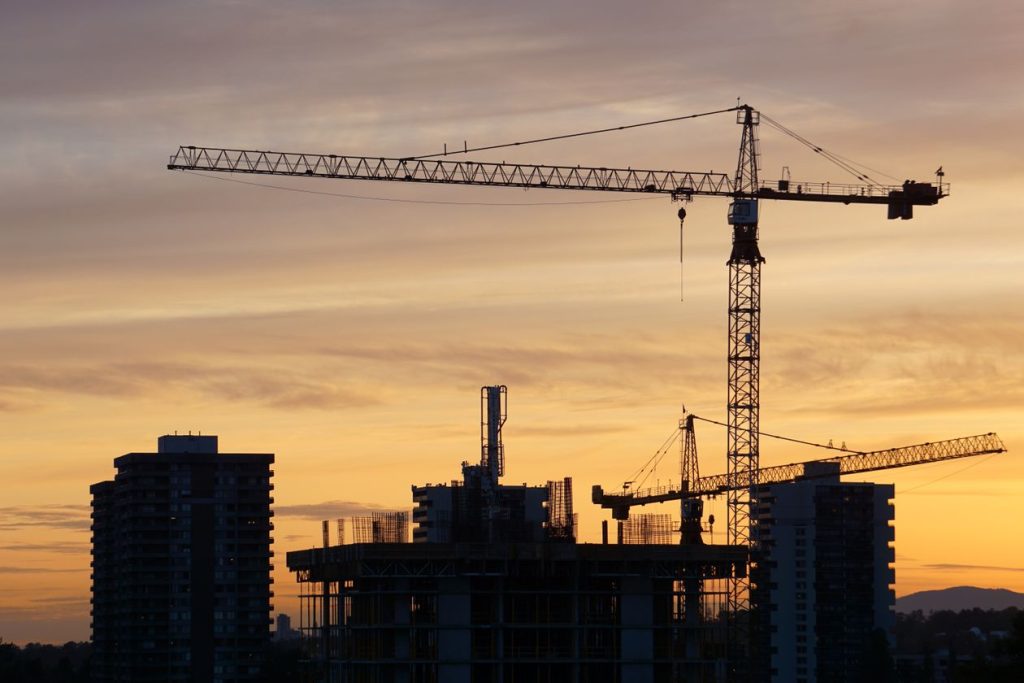 Silhouette of construction cranes and high-rise buildings against a dusk skyline, off-plan property development