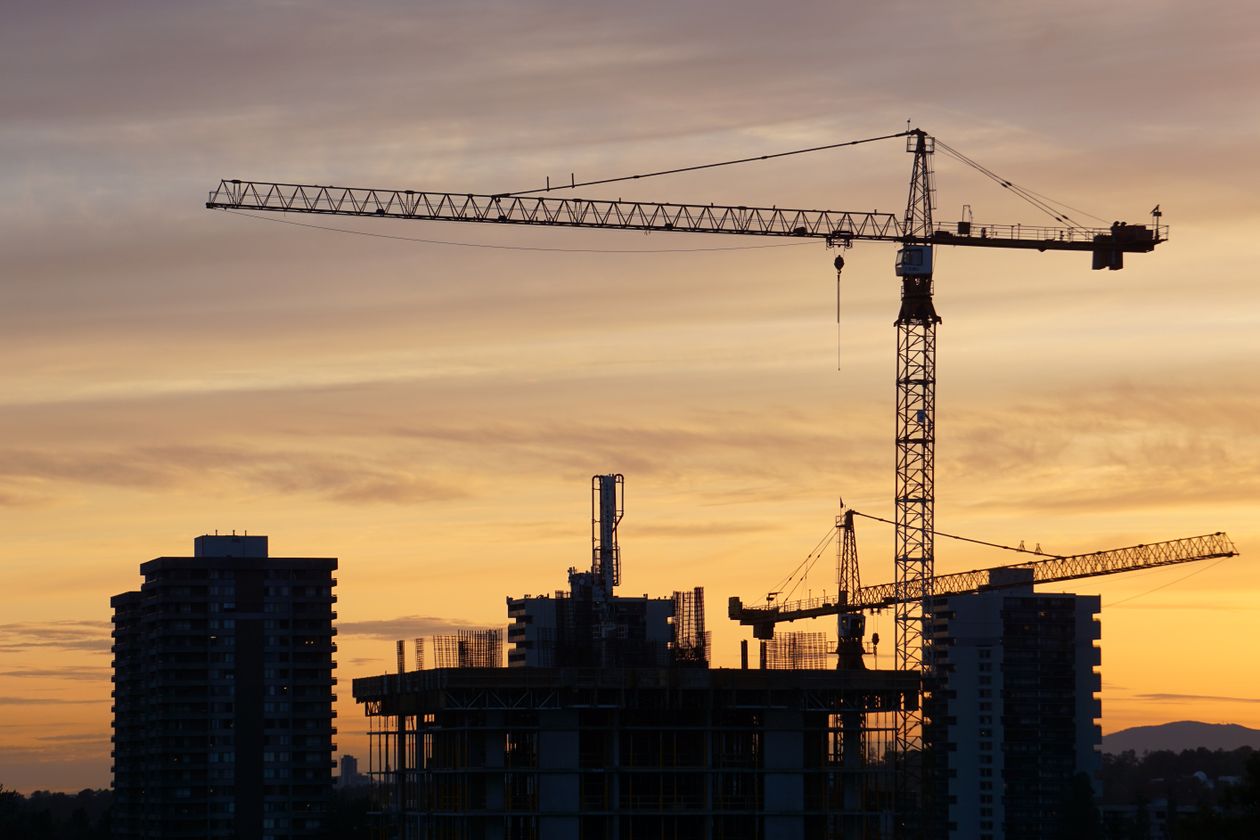 Silhouette of construction cranes and high-rise buildings against a dusk skyline, off-plan property development