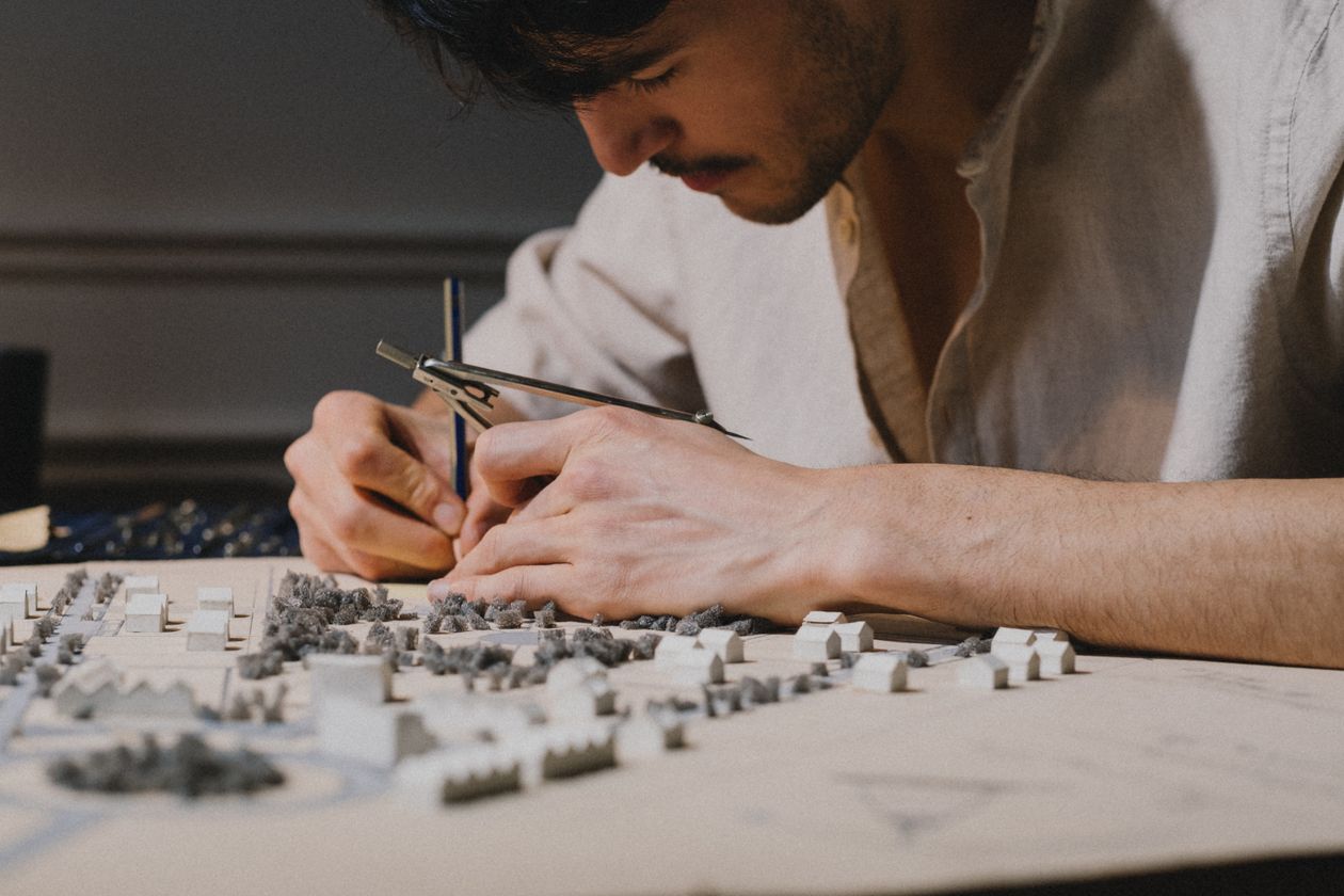 Architect working on a detailed scale model in a design studio, off-plan development sales gallery presentation