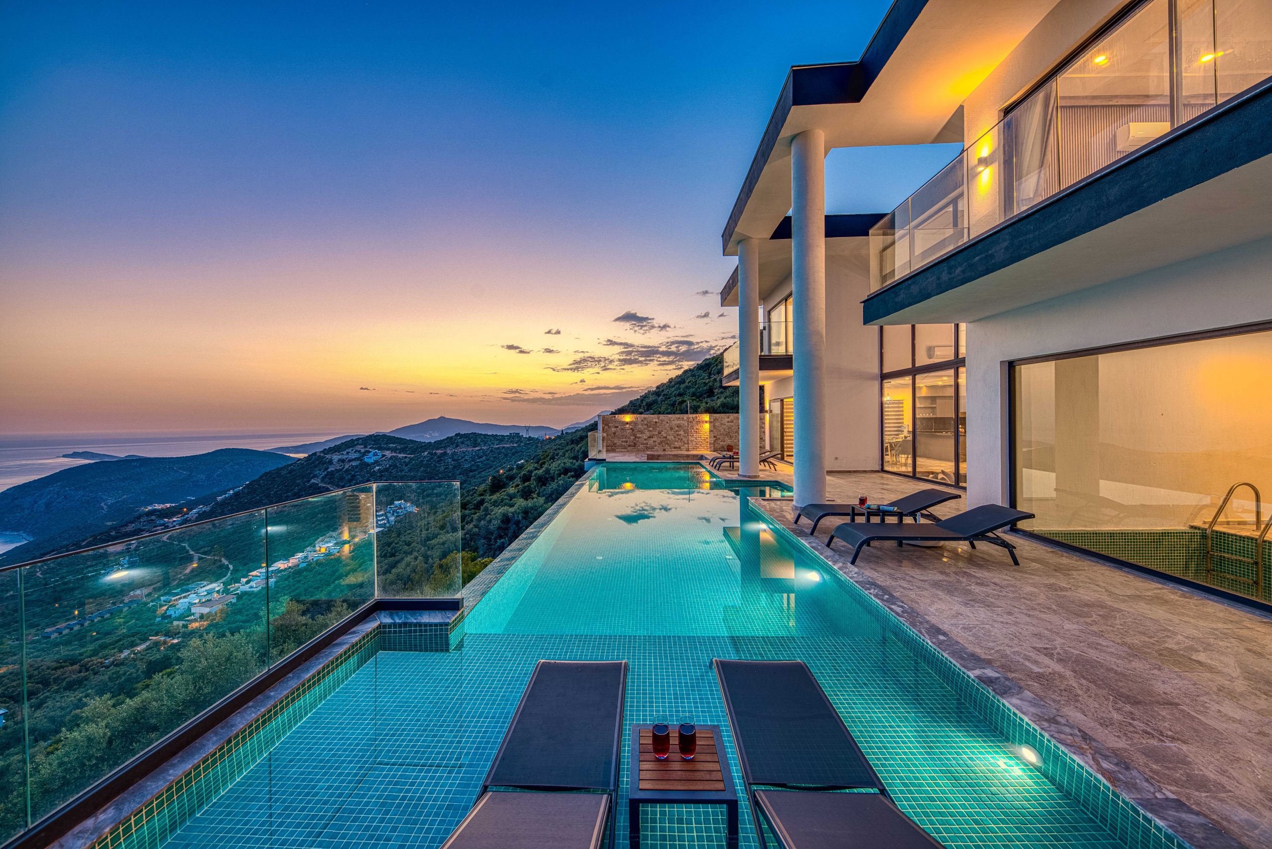 Luxury oceanview villa with infinity pool glowing at sunset twilight, Dubai real estate photography